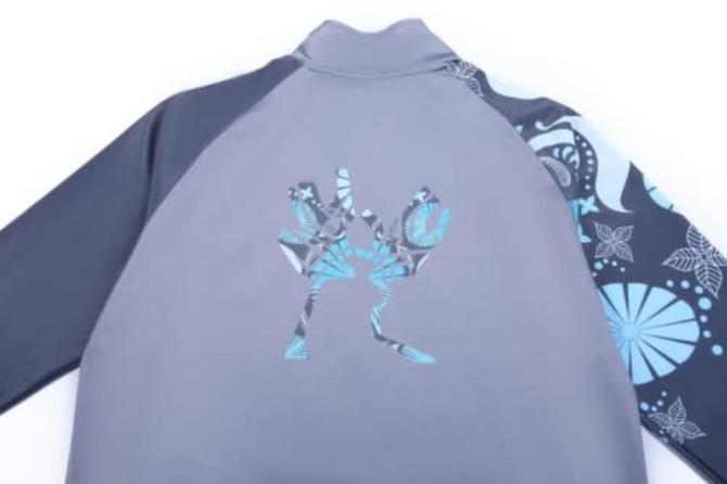 A grey jacket with patterned blue sleeves and a logo on the back, designed for sports uniforms.