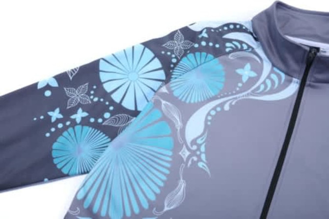 A school wear jacket in grey with blue floral and abstract patterns, featuring a zip closure and a high collar.