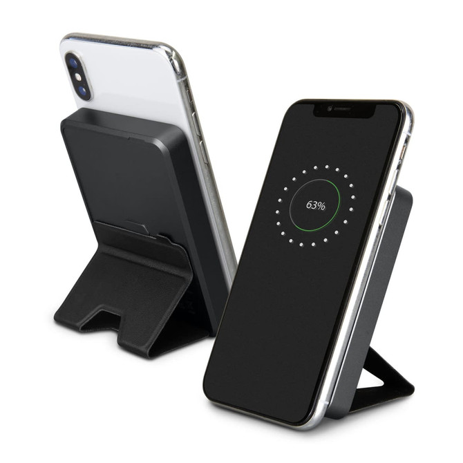 A black wireless charging power bank with a stand, featuring a smartphone displaying a charging indicator.