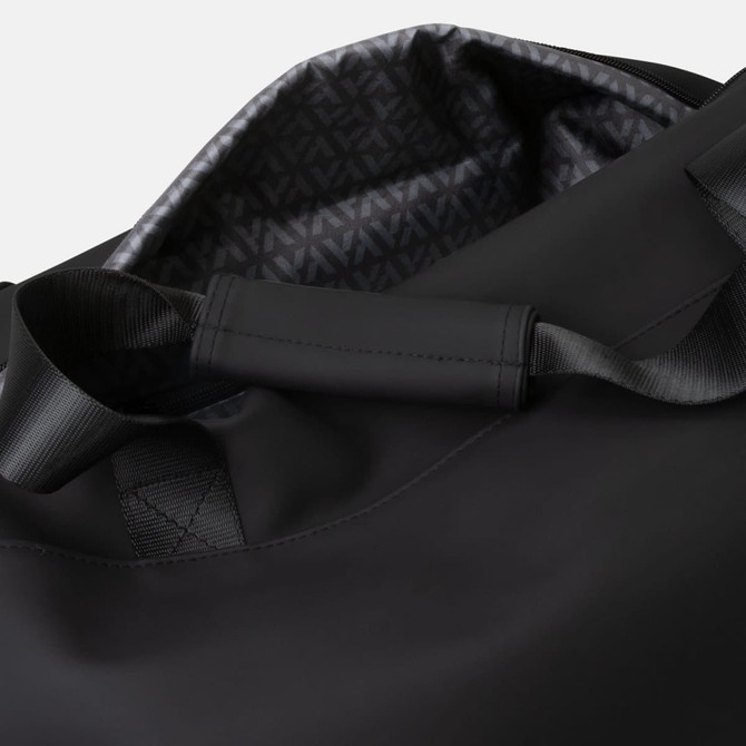 A black soft-touch duffle bag with a patterned interior and sturdy handles. It features a minimalist design and branding.