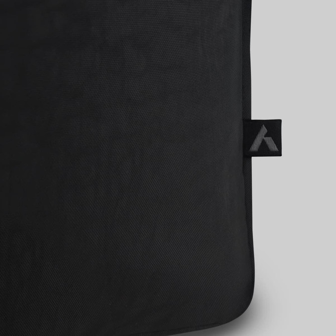 A black tote bag with a textured surface and a small branding tag.