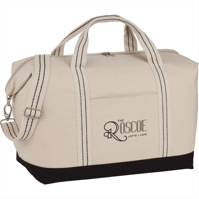 A cream canvas duffel bag with black accents and dual handles, featuring a logo on the side.