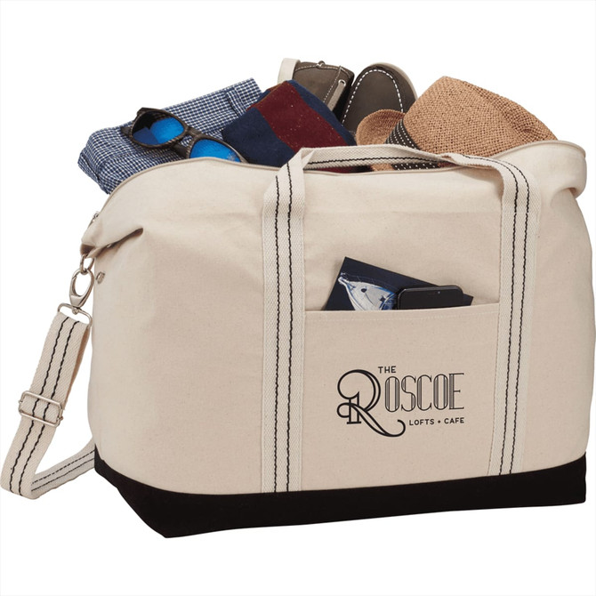 A cream cotton canvas duffel bag with a pocket, filled with clothing and accessories. It has black accents and a logo.