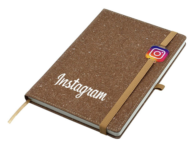 A brown bonded leather notebook with an elastic closure and a logo, featuring a cream interior and ribbon bookmark.
