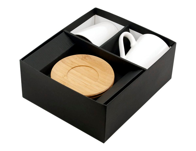 A drinkware set featuring two white coffee mugs and a bamboo saucer in a black presentation box.