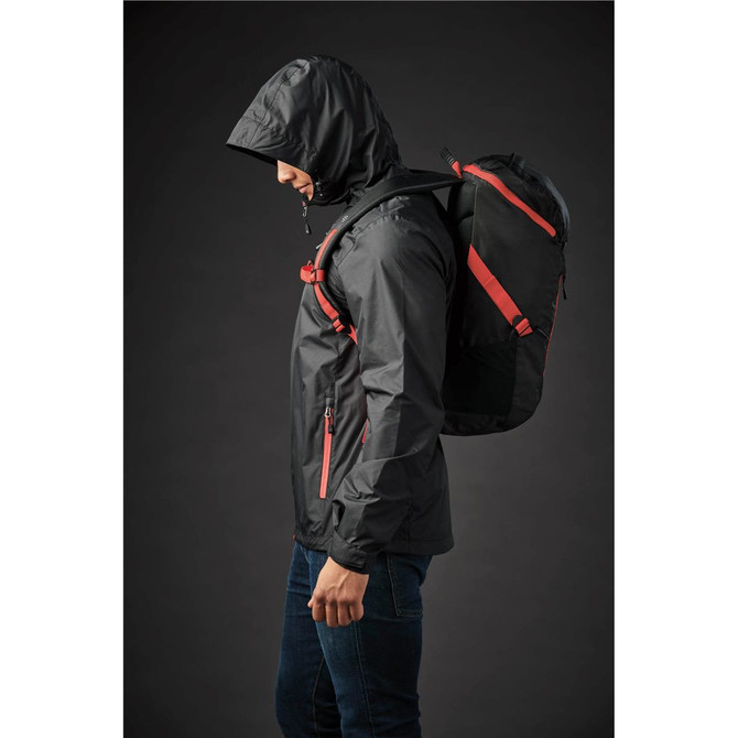 A black Whistler Backpack with red straps is worn by a person in a jacket, shown against a dark background.