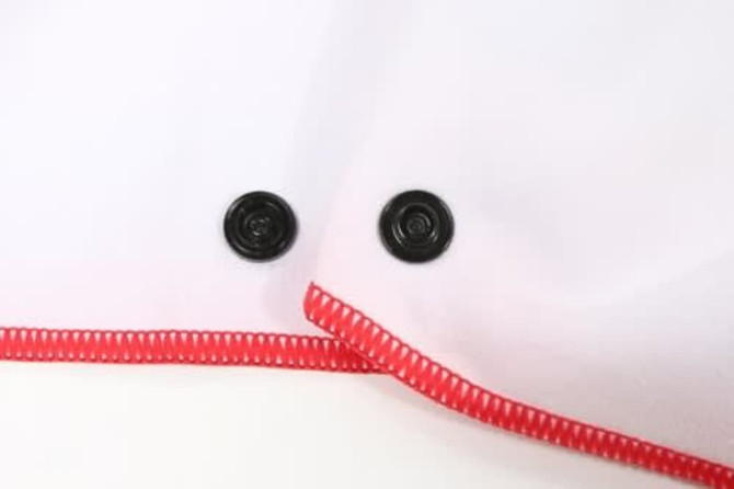 A beach towel in white with a red trim and two black snaps for fastening.