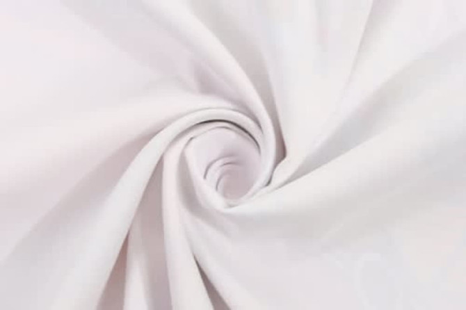 A white beach towel fabric displayed in a swirling pattern, showcasing its soft texture. It features a logo.