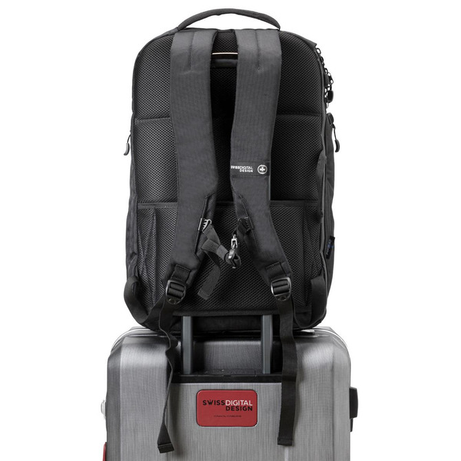 A black backpack with padded straps sits atop a silver suitcase, featuring a branding logo on the front.