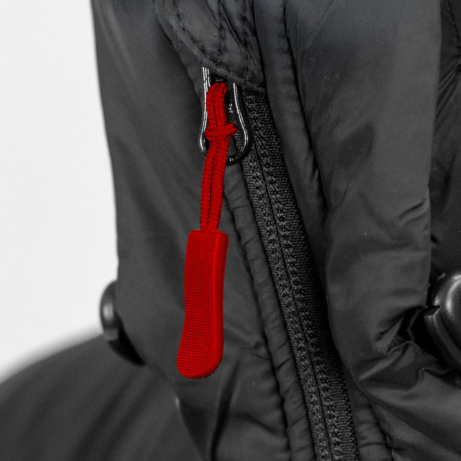 A close-up of a black puffer jacket featuring a red zipper pull and a visible zipper.