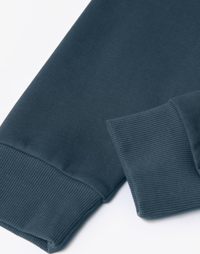 A close-up of a dark teal unisex crew neck sweater, featuring ribbed cuffs and a smooth texture.