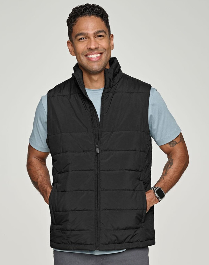 A man wearing a black insulated puffer vest with a 3D cut over a grey shirt, smiling. The vest has a logo.