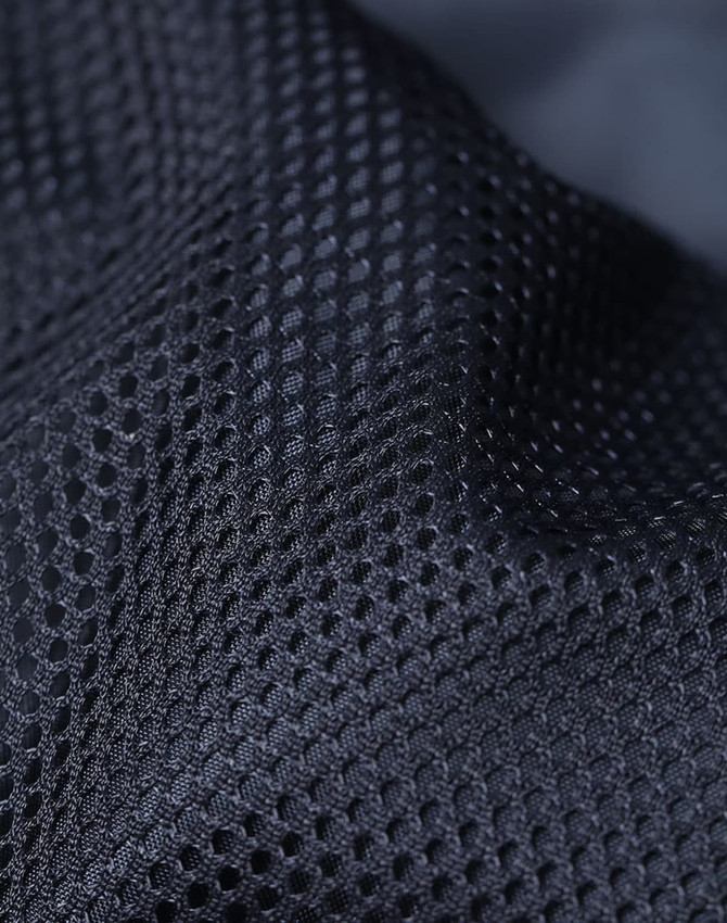 A close-up of textured black mesh fabric featuring a breathable design and a subtle sheen.