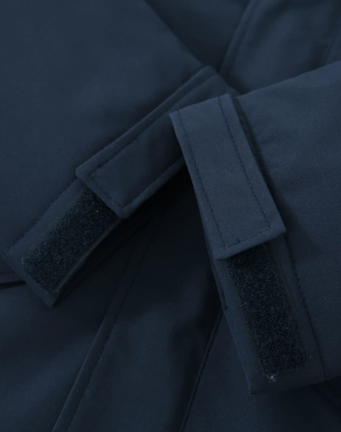 A close-up of a navy unisex quilted waterproof jacket featuring adjustable velcro cuffs and a smooth fabric finish.