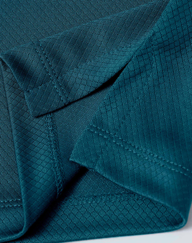 Close-up of a teal sustainable jacquard knit fabric, showcasing the texture and stitching detail of a polo shirt.