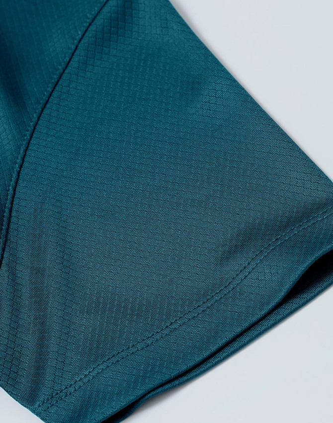 A close-up of a teal sustainable jacquard knit fabric, showcasing the texture of a short-sleeved polo.