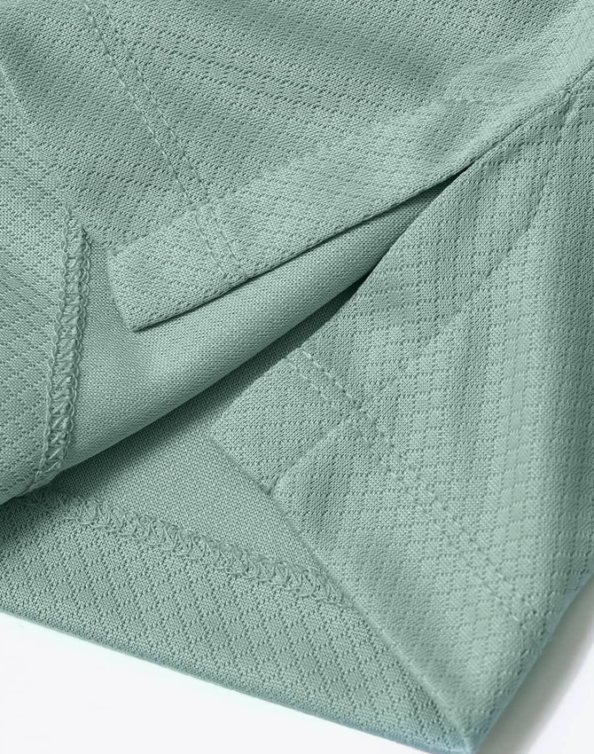 A close-up of a light green sustainable jacquard knit polo shirt featuring textured fabric and stitching details.
