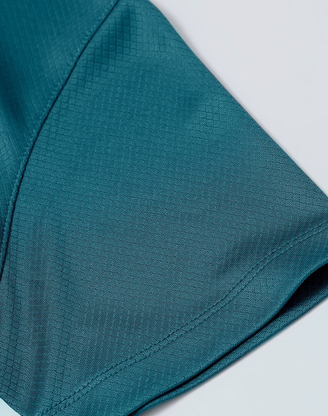 A close-up of a teal jacquard knit fabric featuring a smooth texture and subtle pattern, with a logo present.