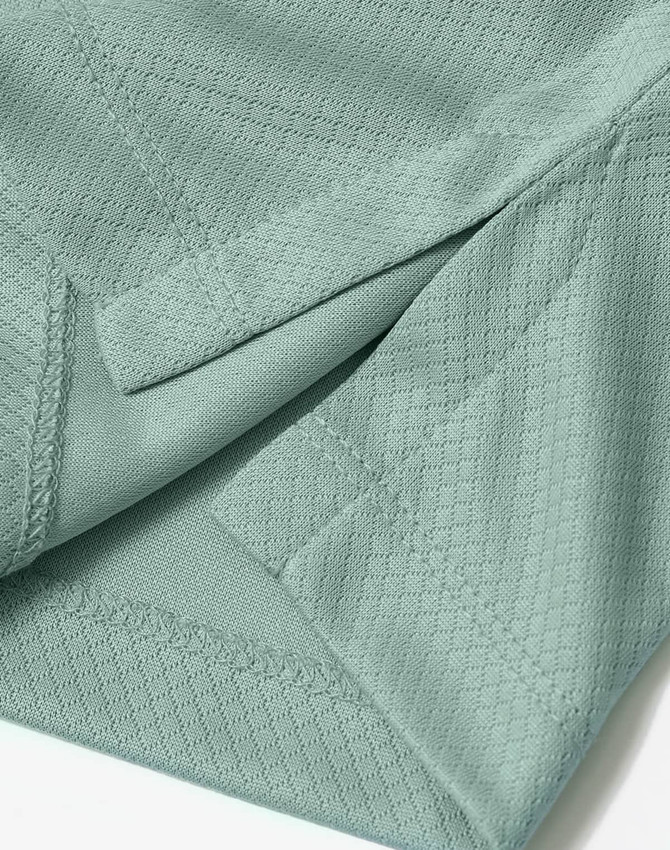 A close-up of a light green sustainable jacquard knit fabric, featuring textured detailing and stitching.