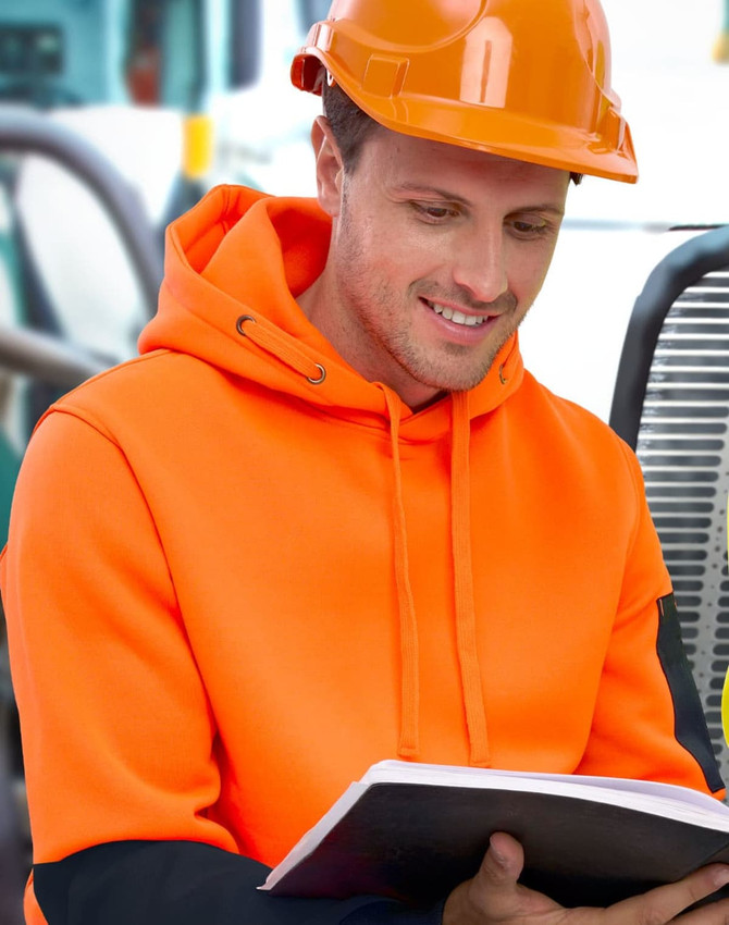 A bright orange and black water-resistant fleece hoodie with a hood, worn by a person in safety gear, reading a book.