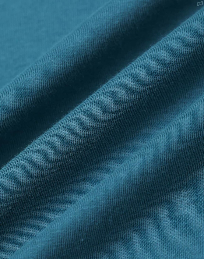 A close-up of a textured fabric in deep teal, showcasing the softness and weave of the premium cotton material.