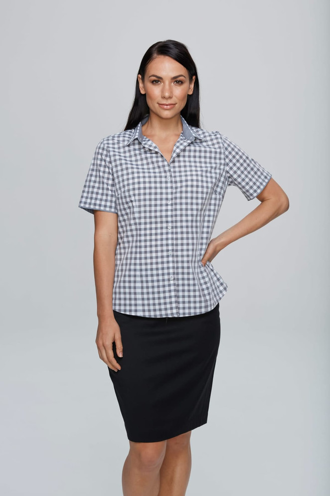 A short-sleeve, button-up shirt in a checkered pattern, featuring a collar, paired with a black skirt.