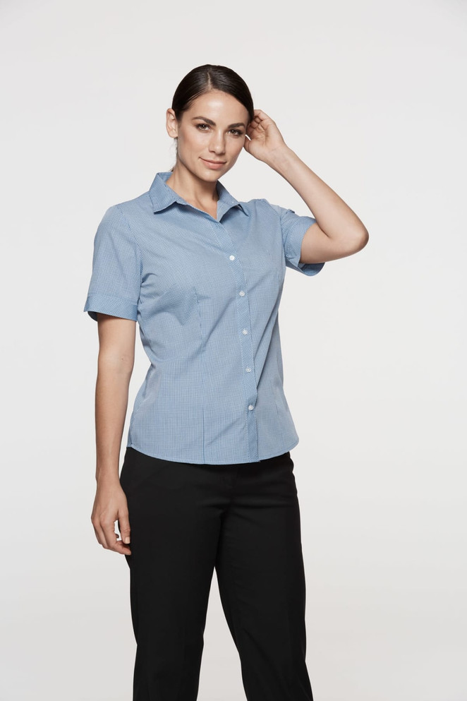 A short-sleeve button-up shirt in blue, worn by a model. The shirt features a collar and is tailored for a fitted look.
