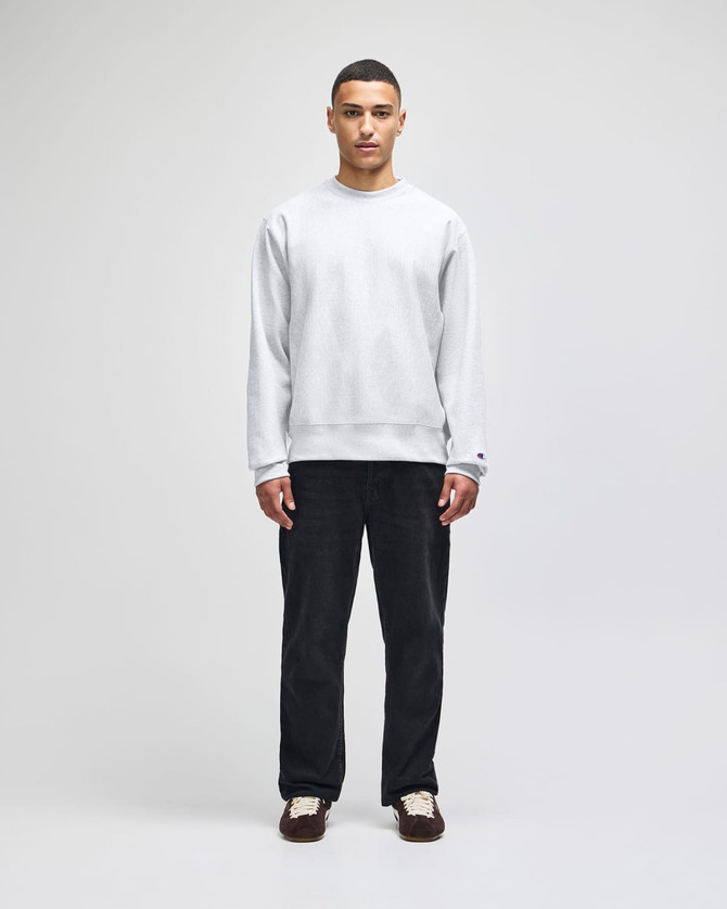 A grey Champion Reverse Weave® adult crew sweatshirt worn by a model with dark trousers and shoes.
