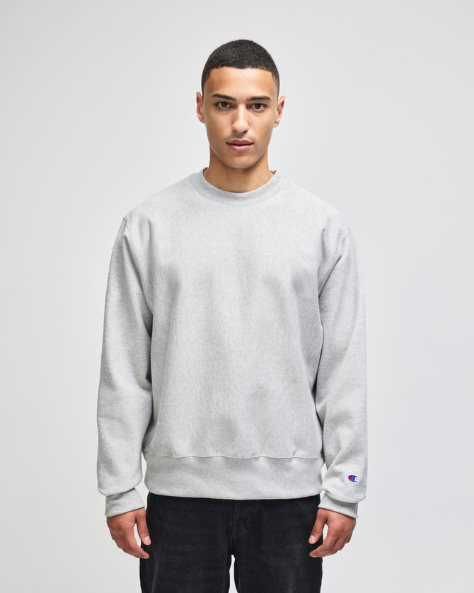 A grey Champion Reverse Weave® adult crew sweatshirt with long sleeves and a logo on the sleeve.