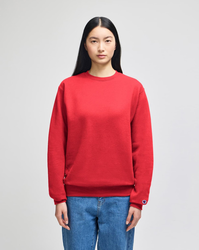 A red crewneck sweatshirt displayed on a model, featuring long sleeves and a logo.