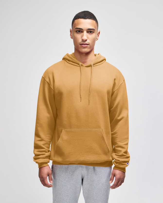 A plain mustard-coloured pullover hooded sweatshirt with a front pocket and a logo. The model is wearing grey pants.