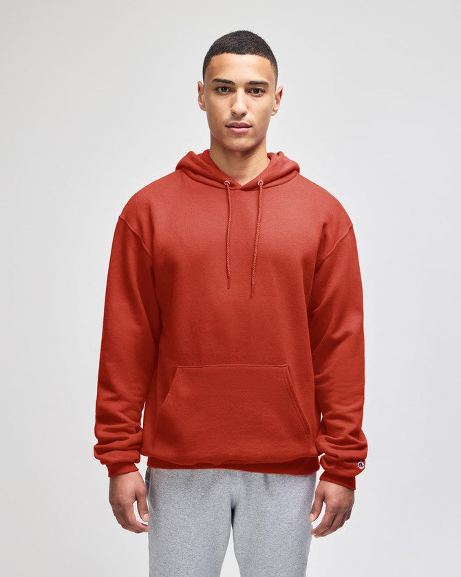A red pullover hooded sweatshirt with a front pocket, modelled by a person wearing grey pants. The sweatshirt has branding.