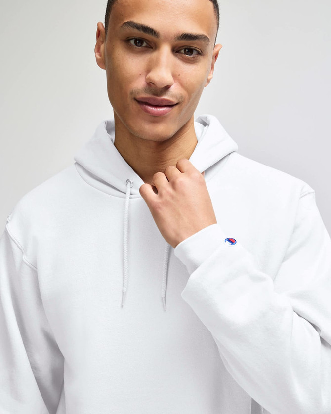 A white pullover hooded sweatshirt with a logo, worn by a person with short hair.