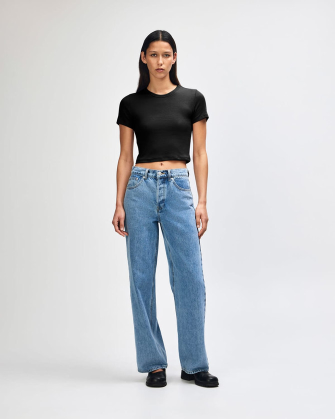 A black crop fitted T-shirt paired with light blue wide-leg jeans, displayed on a model against a plain background.