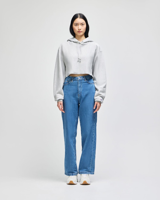 A cropped hoodie in grey with a hood, paired with blue wide-leg jeans and white sneakers.
