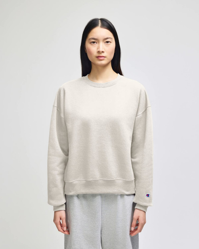 A light grey women's crewneck sweatshirt with a relaxed fit and a logo on one sleeve.