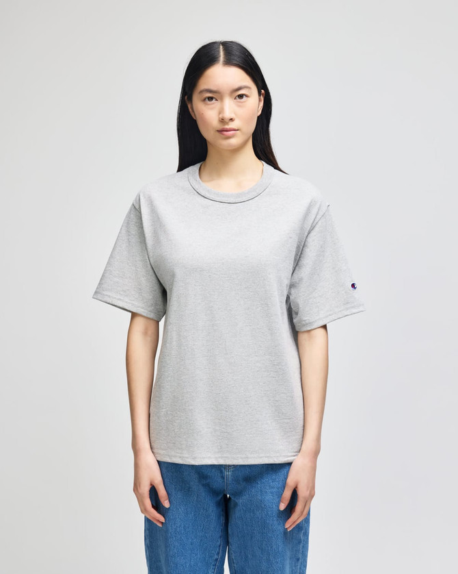 A grey Champion Adult Heritage Jersey T-Shirt on a model, featuring a relaxed fit and short sleeves.
