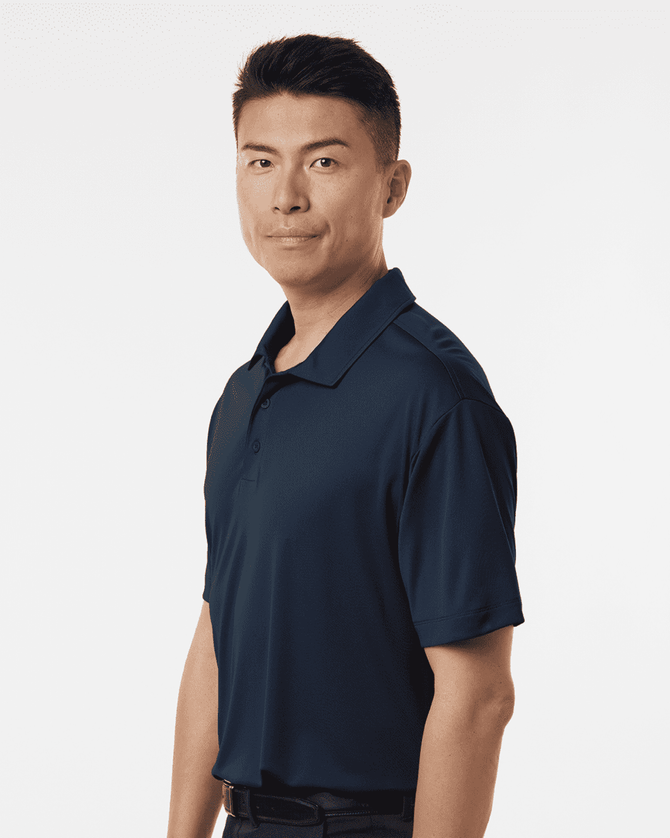 A man models a navy blue polo shirt featuring a collar and short sleeves, with a visible logo.