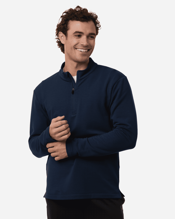 Men's stretch fleece 1/4 zip in navy, featuring a high collar and a relaxed fit. Model smiling while holding hands together.