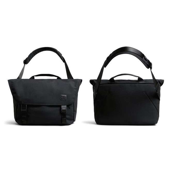 A black messenger bag with adjustable strap, featuring a flap closure and carry handles, along with a subtle logo.