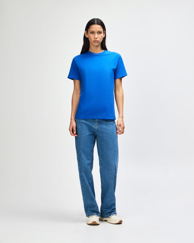 A model wearing a bright blue heavyweight cotton unisex T-shirt paired with light blue jeans.
