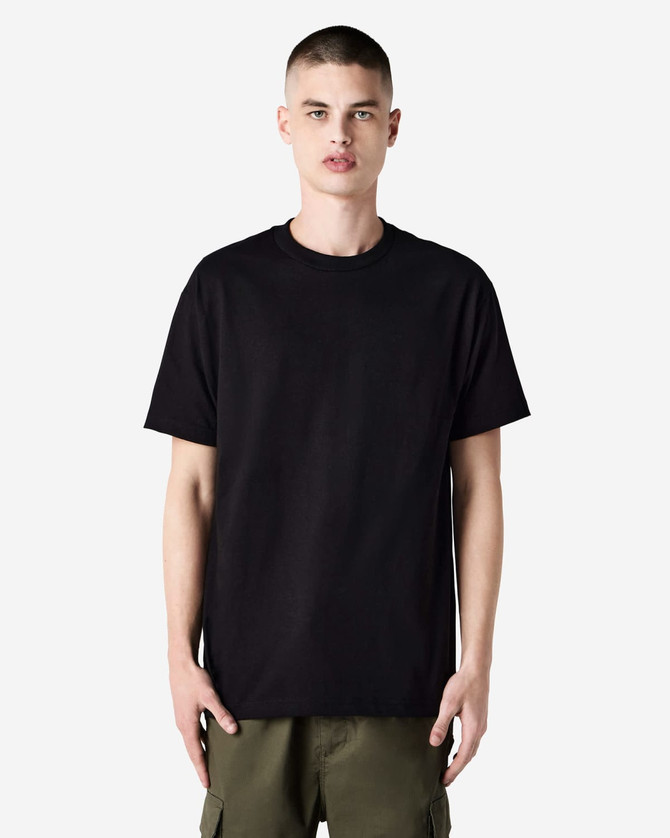 A heavyweight cotton unisex T-shirt in black displayed on a model, featuring a simple design and short sleeves.
