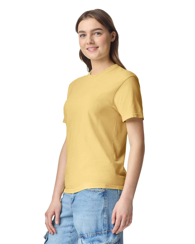 A yellow adult heavyweight T-shirt displayed on a model, featuring a logo. The model is wearing casual denim shorts.