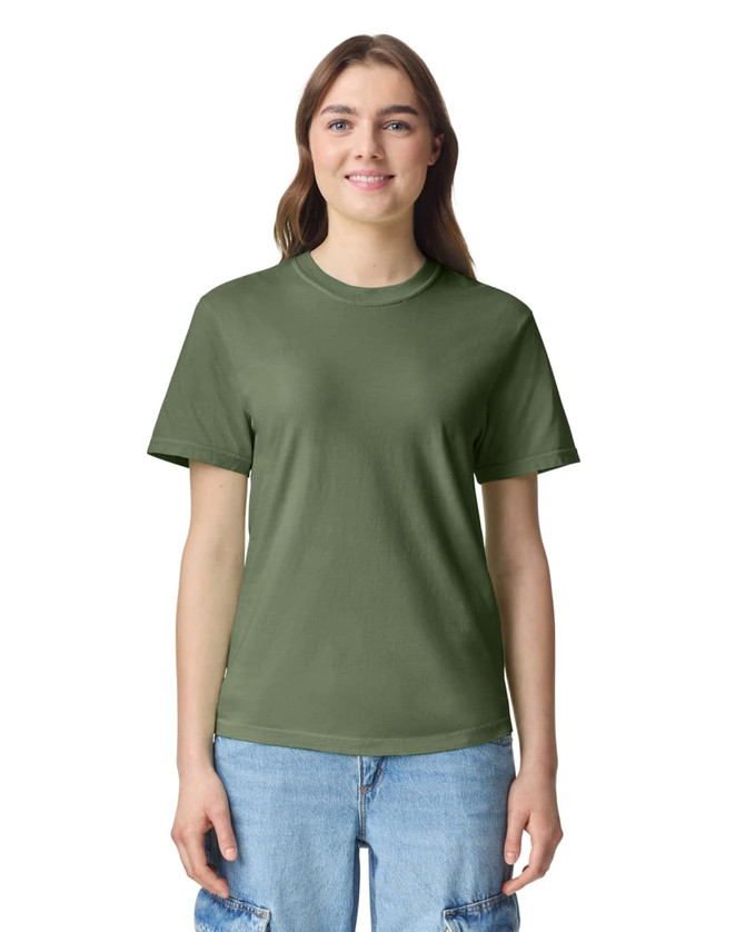 A woman wears an olive green adult heavyweight t-shirt with a casual fit. The shirt features a logo on the front.
