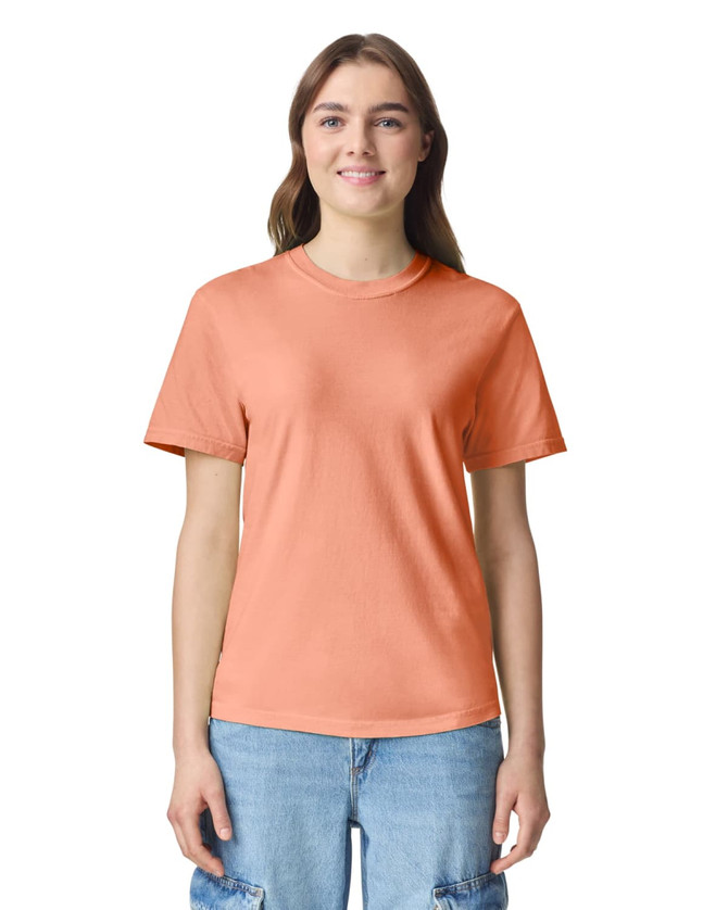 An orange heavyweight adult t-shirt displayed on a model, featuring a simple design and a logo.