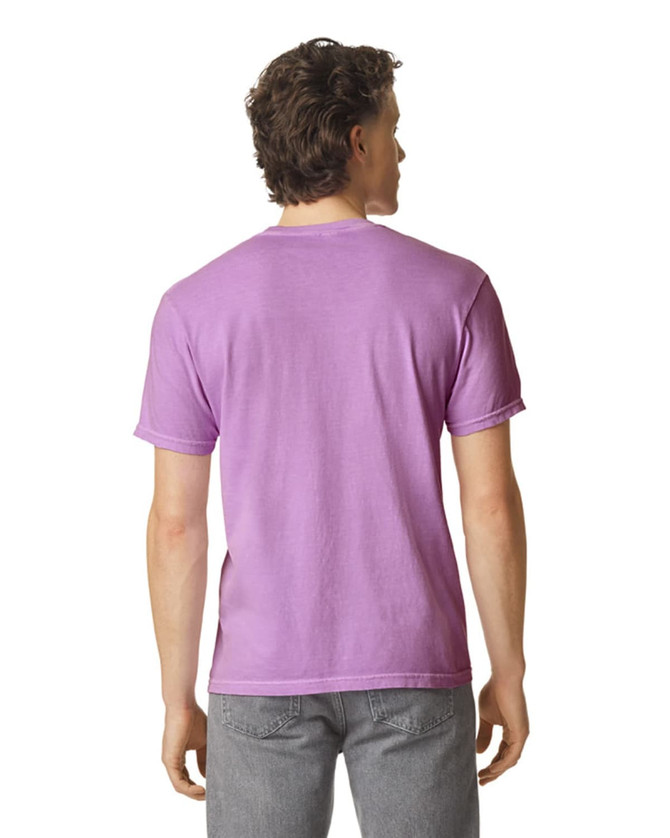 A man wearing a purple heavyweight t-shirt, viewed from the back, with grey pants. The shirt has a logo on it.