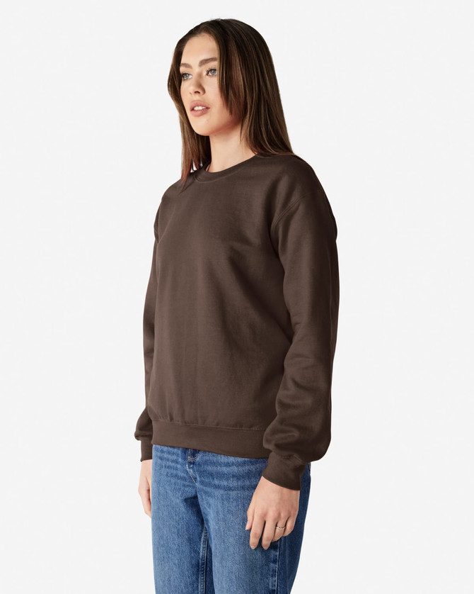 A brown Gildan Heavy Blend adult crewneck sweatshirt worn by a model, paired with blue jeans. The sweatshirt has a simple design.