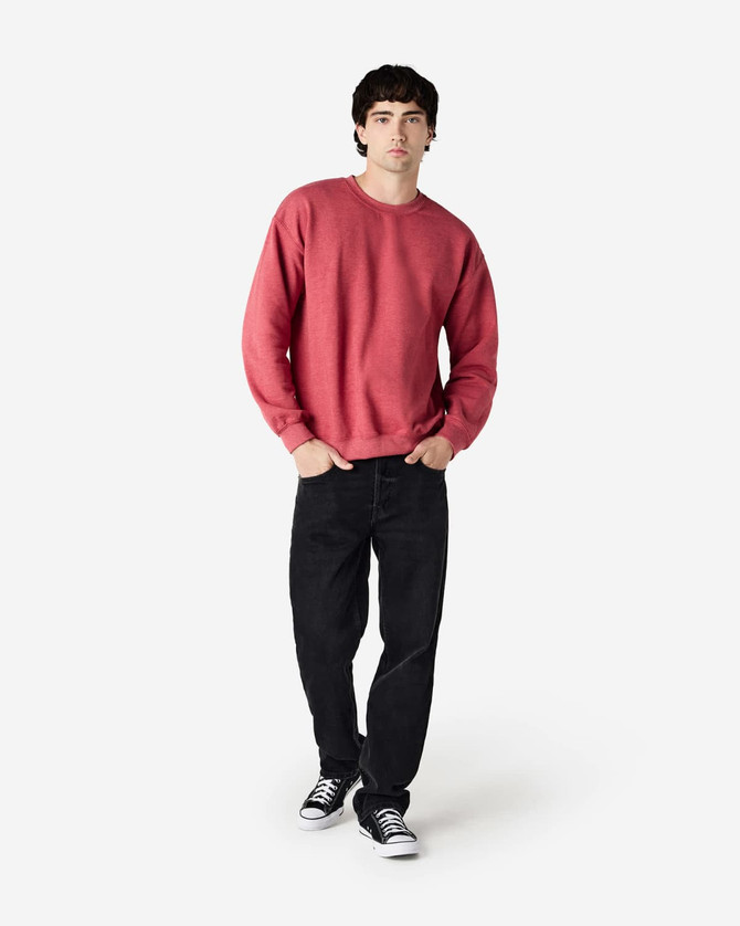 A man wearing a red Gildan Heavy Blend adult crewneck sweatshirt and black jeans, with a logo on the sweatshirt.