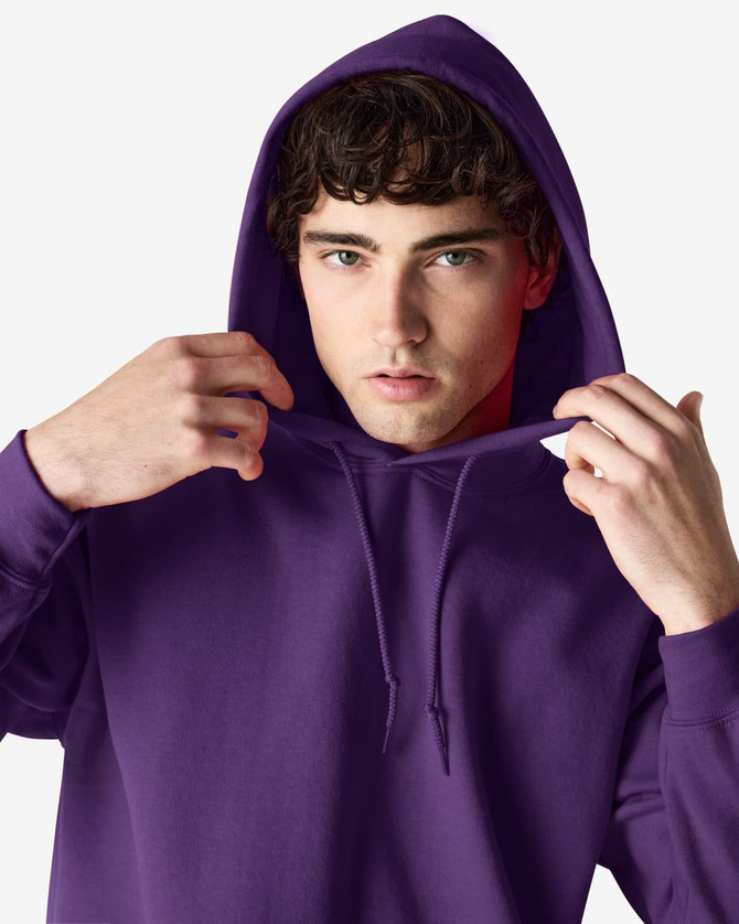 A purple hooded sweatshirt is being worn by a young man, who is pulling the hood over his head.