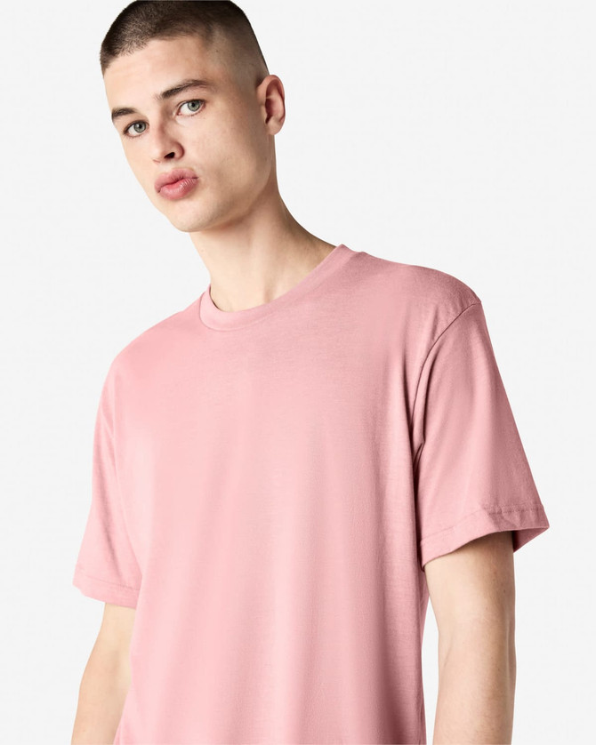 A model wearing a unisex short sleeve t-shirt in a soft pink colour. The shirt features a logo on the sleeve.